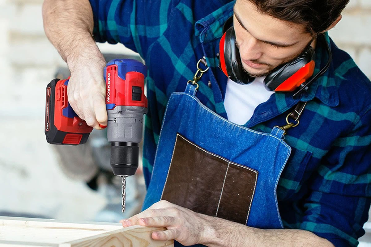Photo d'un jeune homme en plein bricolage, avec une perceuse dans les mains