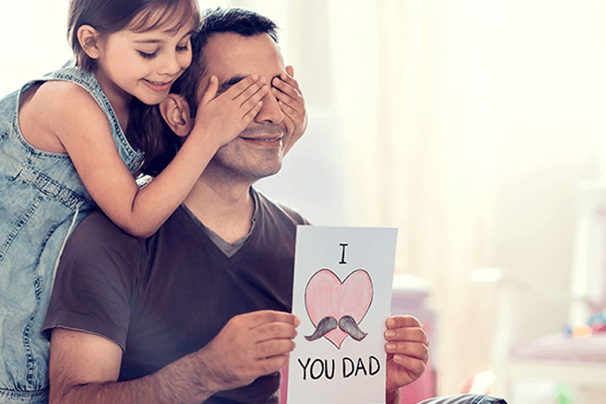 Photo d'une jeune enfant, cachant les yeux de son papa, en lui offrant un tendre dessin