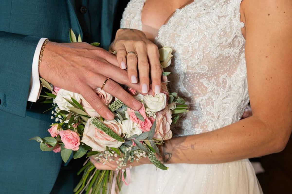 Photo d'un homme et d'une femme le jour de leur mariage, l'alliance à chaque main