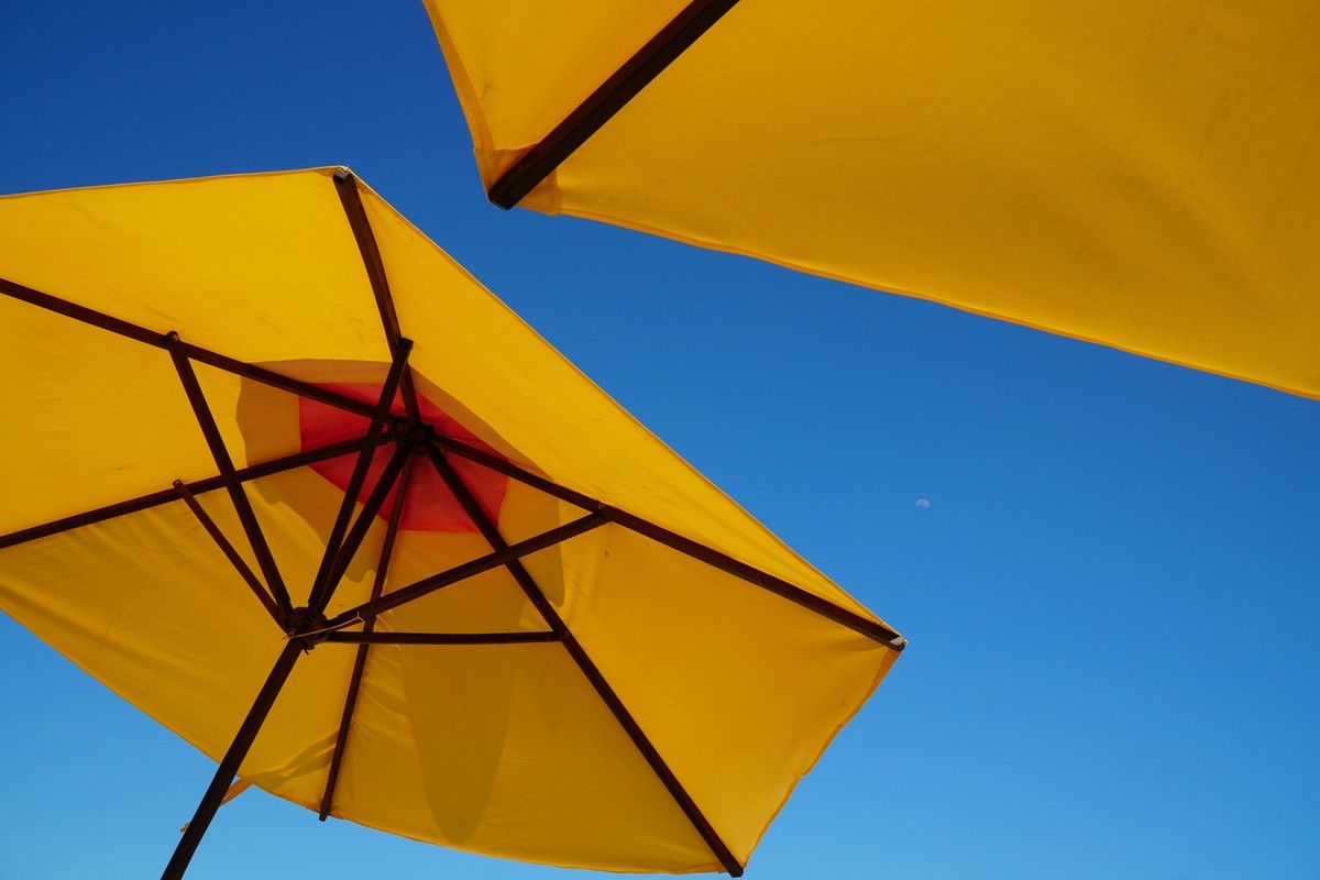 Photo de parasols jaune déployés sous un ciel bleu sans aucun nuage, en France